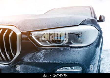 Gros plan sur le phare de luxe de voiture de sport garé à l'extérieur le jour froid de l'hiver. Technologie moderne de lampe laser LED. Véhicule recouvert de givre et Banque D'Images