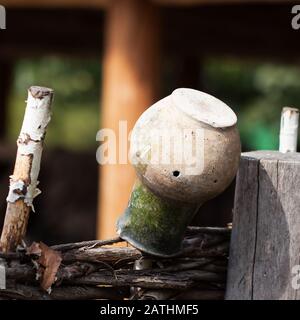 Village, clôture rustique avec eau, vieille carafe en argile. Scène rurale Banque D'Images