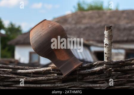 Old Clay Jug sur une clôture en osier, style rustique, paysage rural Banque D'Images