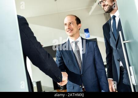 Un groupe de gens d'affaires confiants saluent avec une poignée de main lors d'une réunion d'affaires dans un bureau moderne ou fermant l'accord de transaction en se secouant les mains. Banque D'Images