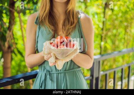 Tomates dans un sac réutilisable entre les mains d'une jeune femme. Concept zéro déchet Banque D'Images