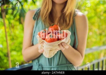 Tomates dans un sac réutilisable entre les mains d'une jeune femme. Concept zéro déchet Banque D'Images