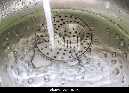 L'eau courante d'un robinet d'eau dans un évier de cuisine métallique Banque D'Images