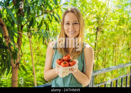 Tomates dans un sac réutilisable entre les mains d'une jeune femme. Concept zéro déchet Banque D'Images