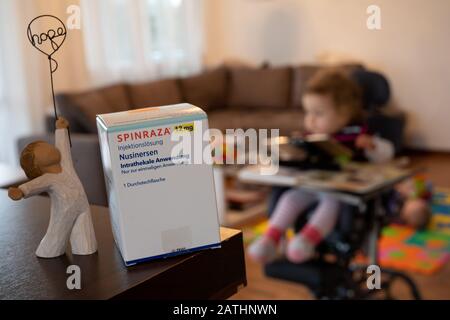 Backnang, Allemagne. 3 février 2020. Illustration - 03 février 2020, Bade-Wuerttemberg, Backnang: Un enfant souffrant d'atrophie spinale musculaire (SMA) est assis dans une chaise de thérapie. Au premier plan se trouve une boîte de la drogue Spinraza à côté d'une sculpture d'ange avec le mot "espoir". Les enfants allemands ont maintenant la chance de gagner une thérapie génique pour les bébés en phase terminale. La société pharmaceutique suisse Novartis a commencé la tombola d'un traitement avec Zolgensma pour 100 enfants le 03.02.2020. C'est le médicament le plus cher au monde, avec environ deux millions d'euros pour une dose. Le traitement est f Banque D'Images