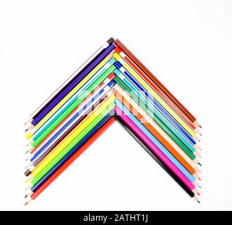 Un tas de crayons de bois et de crayons de couleur différents empilés ensemble pour faire une flèche pointant vers le haut. Banque D'Images
