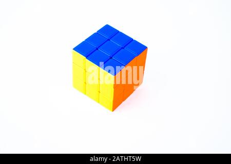 Portrait d'un cube de 3 x 3 rubik résolu dans un fond blanc isolé qui affiche des couleurs bleu, orange et jaune. Banque D'Images