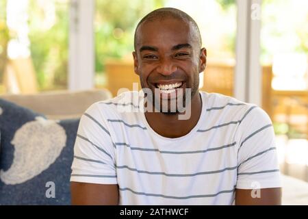 Jeune homme souriant à l'appareil photo à la maison Banque D'Images
