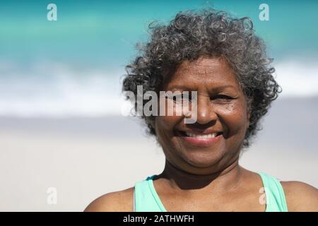 Vieille femme souriante à la plage Banque D'Images