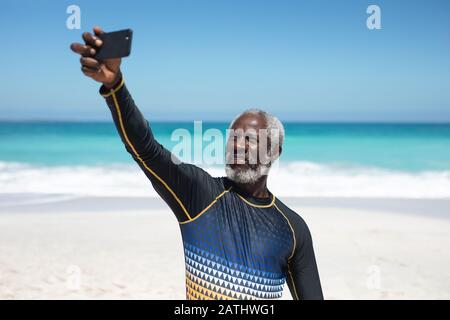 Vieil homme prenant des selfies à la plage Banque D'Images