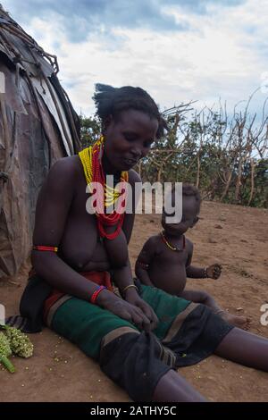 Omorate, Ethiopie - Nov 2018: Femme de la tribu Dassanech avec un enfant devant la maison tribale. Vallée de l'Omo Banque D'Images