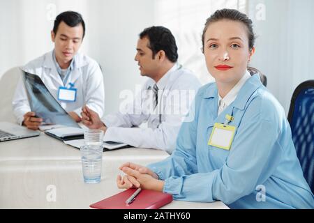 Une femme généraliste sûre d'elle est assise sur une grande table dans le salon médecins Banque D'Images