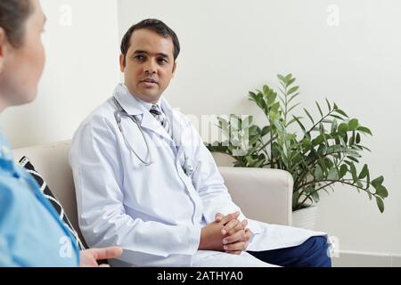 Un médecin généraliste indien sérieux parle à une collègue de sexe féminin dans la salle de séjour des médecins Banque D'Images