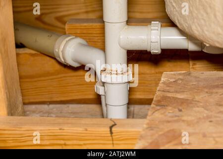 Vieux tuyaux de plomberie en plastique qui fuient sous le plancher pour la baignoire et la douche de salle de bains. Concept de DYI entretien à domicile, réparation, rénovation Banque D'Images