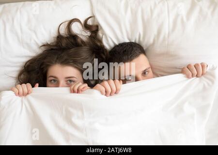 Vue de dessus du couple allongé dans le lit sous la couverture. Banque D'Images