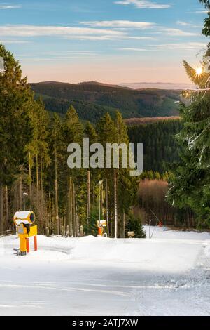 Belle piste de ski dans la forêt. Des canons à neige ont fourni une couche de neige. La journée d'hiver avec un beau temps vous invite à des sports d'hiver. Banque D'Images