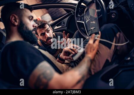 Diagnostic voiture.Mécanique utilisant un ordinateur portable sur voiture au garage de réparation. Banque D'Images