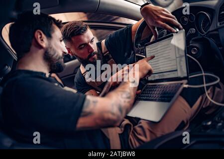 Diagnostic voiture.Mécanique utilisant un ordinateur portable sur voiture au garage de réparation. Banque D'Images