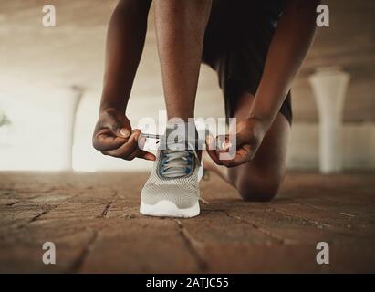 Image rognée des mains nouant des lacets de sneaker sur la surface du pavé Banque D'Images