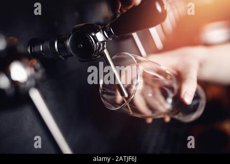 Le barman verse de la bière sombre dans le verre. Focalisation sélective sur le robinet pour les boissons alcoolisées artisanales dans le pub Banque D'Images