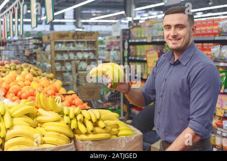 Homme avec des bananes dans le magasin de fruits d'épicerie. Des aliments sains. Concept de shopping Banque D'Images