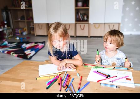 Petit garçon avec dessin de sœur et stylos-feutres Banque D'Images