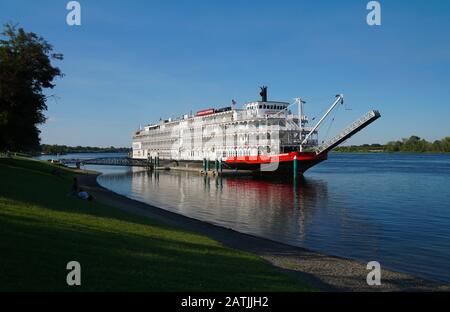 Un beau vieux paddleboat est amarré le long d'un parc en bord de rivière lors d'une journée d'été paresseuse. Banque D'Images