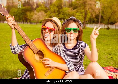 Joyeuses filles joyeux pique-nique et jouant à la guitare Banque D'Images