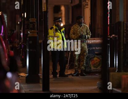 Un policier et un membre des forces armées de Dean Street dans le centre de Londres après la découverte d'une bombe de la seconde Guerre mondiale. Banque D'Images