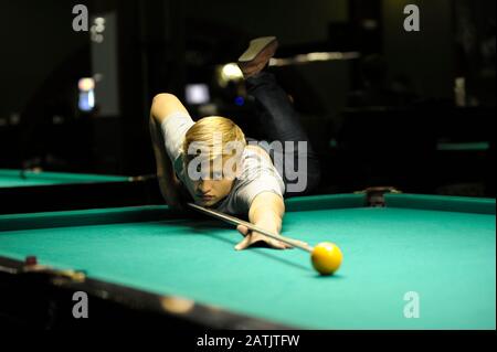 Le joueur de billard masculin est prêt à jouer une balle avec un bâton de repère en utilisant un repos Banque D'Images