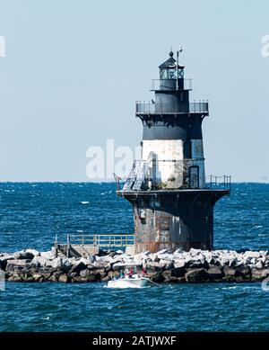 Les gens sont dans une petite pêche en bateau devant le phare de Orient point une journée venteuse. Banque D'Images
