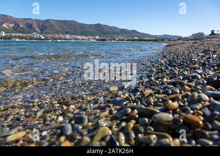 Galets mouillés sur la plage de Gelendzhik au premier plan, grands. Ensuite, nous voyons la baie de Gelendzhik et les montagnes du Caucase. Été, matin, soleil Banque D'Images