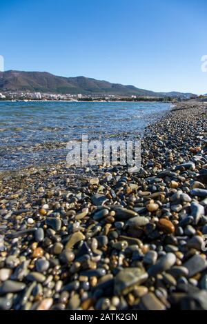 Galets mouillés sur la plage de Gelendzhik au premier plan, grands. Ensuite, nous voyons la baie de Gelendzhik et les montagnes du Caucase. Été, matin, soleil Banque D'Images