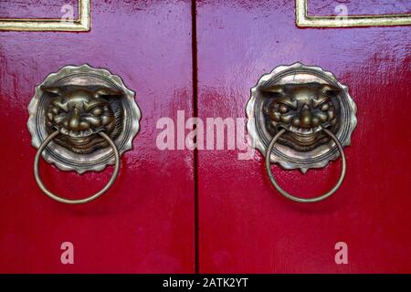 Porte en bronze knocker sur la porte rouge de la salle d'assemblée de Fukian ou de Phuc Kien dans la ville ancienne de Hoi An dans la province de Quang Nam au Vietnam Banque D'Images