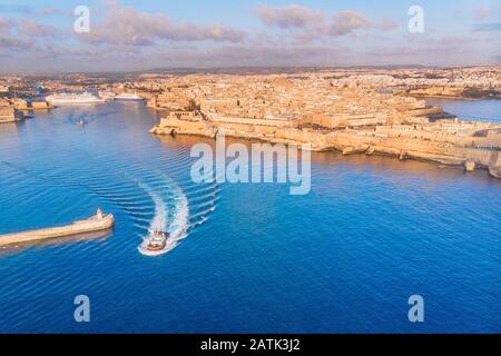 Tugboat navigue pour rencontrer le navire de ligne ou de cargaison dans le port de Malte la Valette. Vue aérienne Banque D'Images