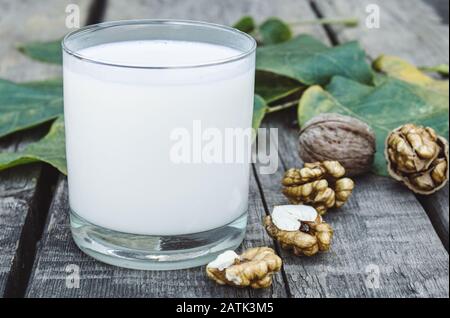 Un verre de lait blanc et de noix sur une vieille table en bois. Lait de légumes à base de noix. Éco-nourriture. Le keto est en train de boire. Banque D'Images