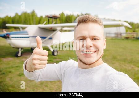 Un bon pilote touristique fait une photo de selfie sur fond d'avion. Voyage concept par transport privé Banque D'Images