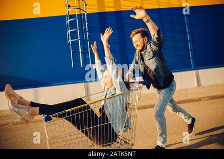 Un couple de jeunes familles heureux est géré avec un chariot pour faire du shopping dans un supermarché. Concept de style de vie Banque D'Images