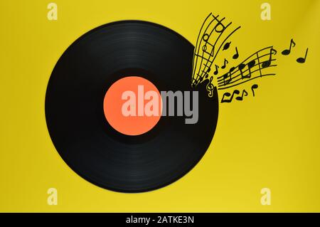 ancien disque vinyle noir avec étiquette orange vierge centrée sur fond jaune avec notes et rasages venant de lui Banque D'Images