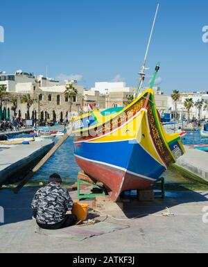 MARSAXLOKK, MALTE. 30 décembre 2019. Un pêcheur rafraîchit les yeux peints d'Osiris sur la prow de son maltais 'Luzzu' - l'un des couleurs vives Banque D'Images