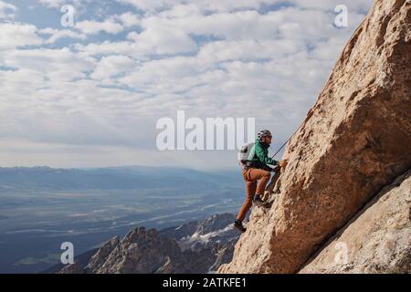 Un grimpeur de roche mâle monte sur la route Exum Ridge sur le Grand Teton. Banque D'Images