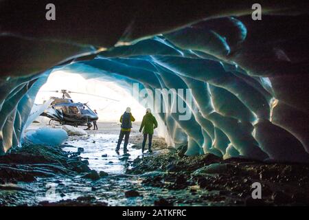 Vue arrière d'un couple qui découvre une grotte de glace lors d'une visite en hélicoptère de luxe Banque D'Images