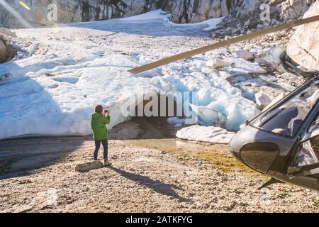 jeune femme prenant la photo d'une grotte de glace pendant le vol en hélicoptère. Banque D'Images