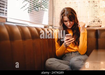 Jeune femme utilisant un smartphone assis dans un café Banque D'Images