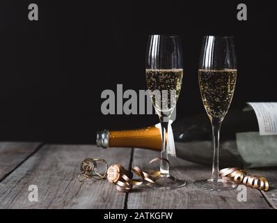 Deux verres de champagne et une bouteille vide avec fond noir. Banque D'Images