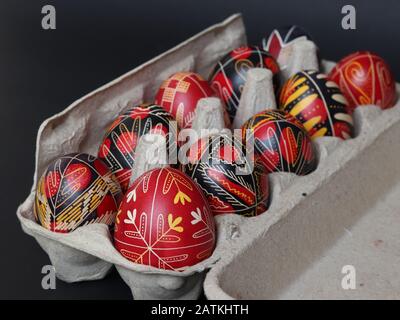 Brasov/Roumanie - 2/1/2020: Traditionnel noir et rouge roumain a peint des œufs de pâques dans un carton d'œufs isolé sur fond noir, fait à la main, décoré Banque D'Images