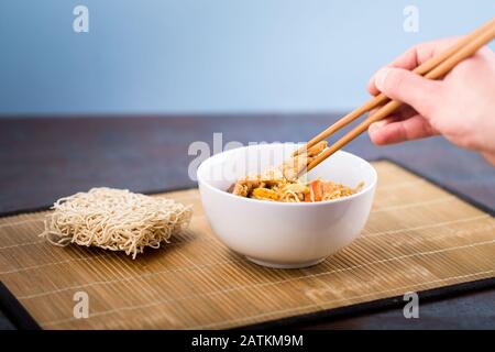 Nouilles chinoises séchées avec viande dans le plat. Baguettes en bambou. Cuisine asiatique. Banque D'Images