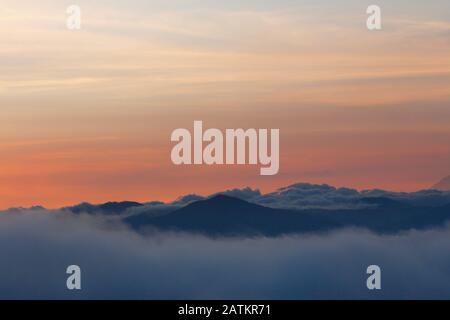 Coucher de soleil avec ciel coloré et de nombreux nuages au-dessus des montagnes Banque D'Images