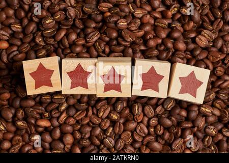 Note abstraite de cinq étoiles sur des cubes de bois sur des grains de café. Le concept du meilleur café. Gros plan. Banque D'Images