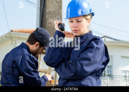 technicien féminin utilisant un talkie-walkie à l'extérieur Banque D'Images